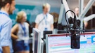 Mikrofon vor Bildschirm; im Hintergrund Menschen | Bild: BR / Lisa Hinder